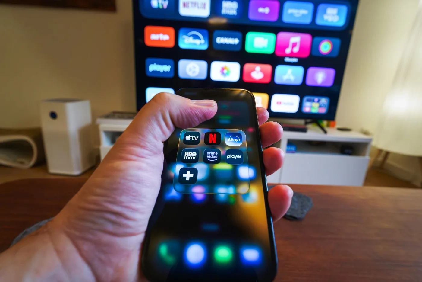 Ruka s telefonem a streamovací aplikace na TV