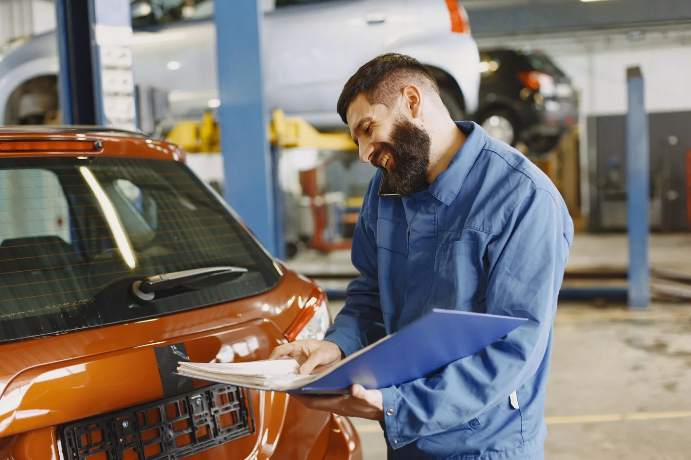 Mechanik s dokumenty kontroluje auto v servisu