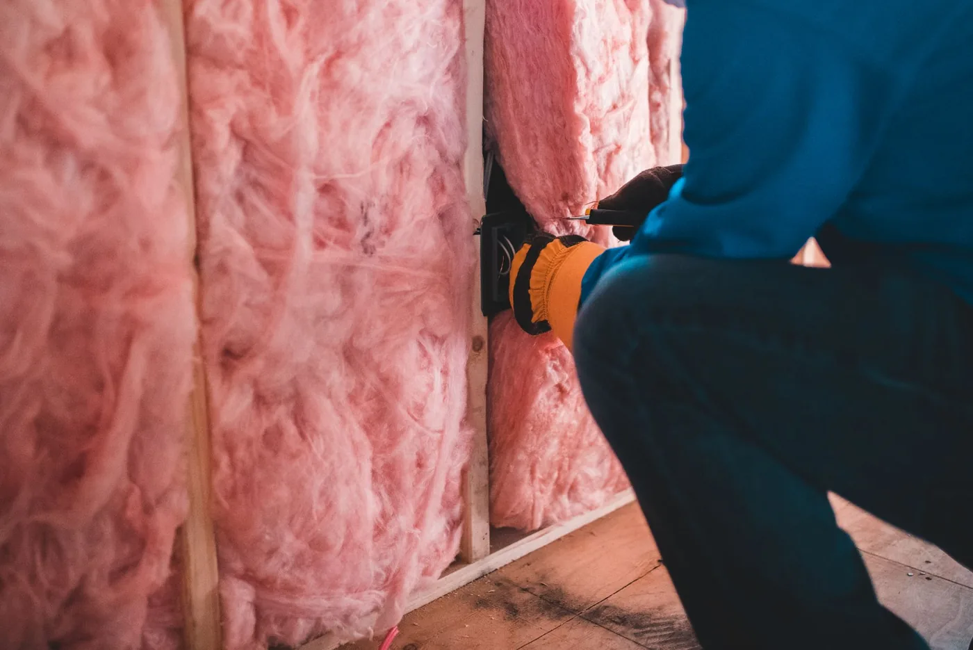 Dělník zateplující stěnu růžovou minerální vlnou