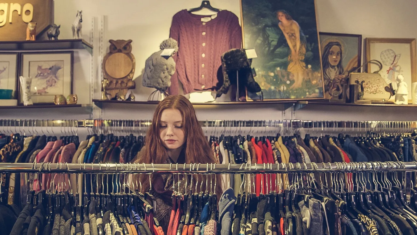 Žena prohlíží oblečení ve vintage obchodě